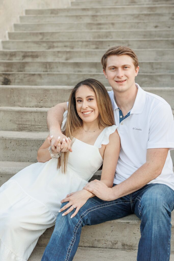 male and female couple pose for engagement photos sitting on concrete stairs