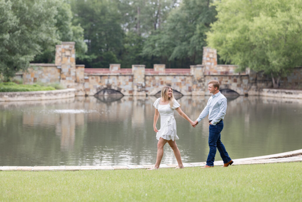 Couple dressed in jeans and white dress walk hand in hand with Ava leading, posing for the woodlands engagement photos