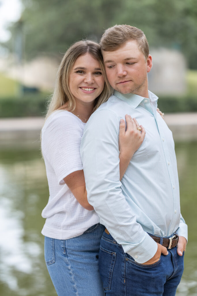 Couple dressed in jeans and white shirts pose for the woodlands engagement photos near the woodlands waterway